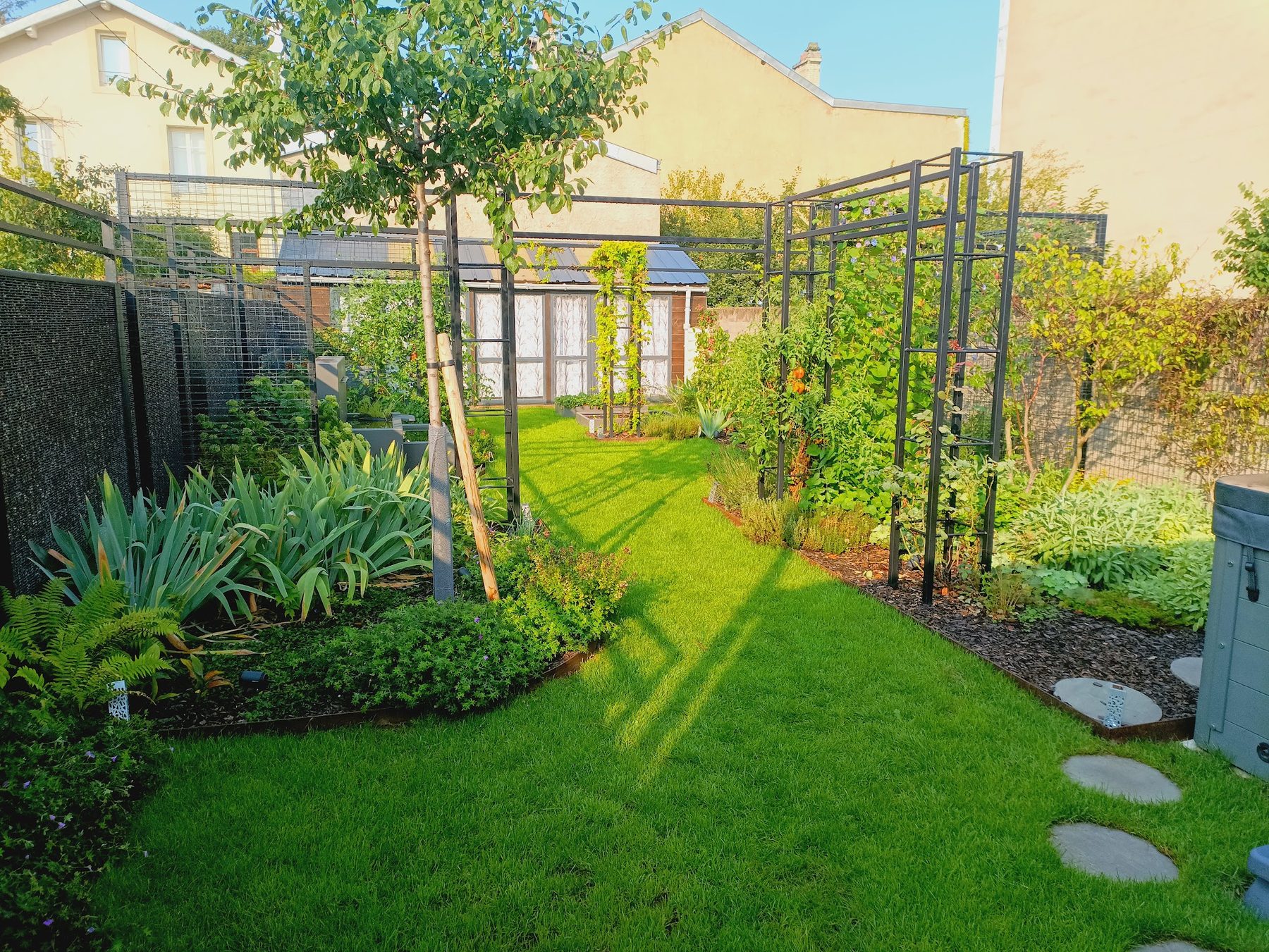Jardin aménagé par L'Ecrin Vert : pelouse, massifs bordés d'acier, pergola métallique