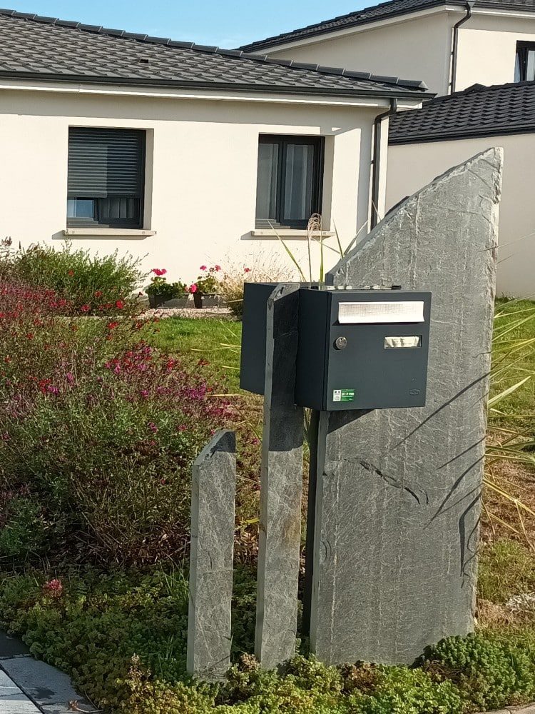 Boîte aux lettres posée entre des pierres levées de schiste